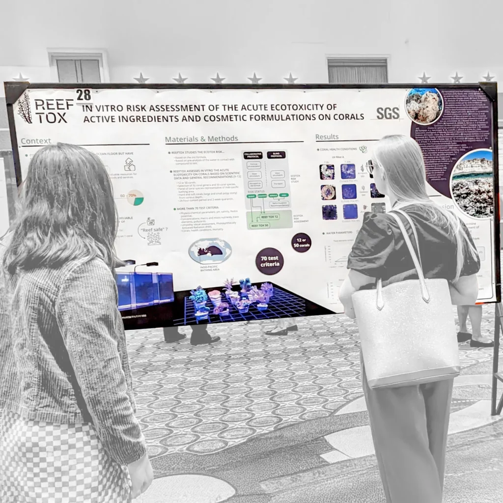 Photo du poster scientifique ReefTox expos&eacute; lors d&rsquo;un congr&egrave;s, avec deux participantes observant les r&eacute;sultats du test cosm&eacute;tique sur coraux.